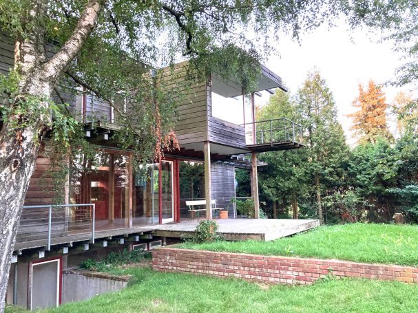 Seitenansicht vom Garten Moderne Holzarchitektur mit großen Fenstern und einem begrünten Außenbereich.